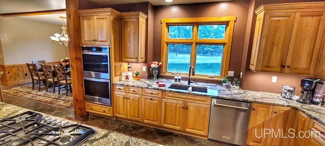 kitchen with an inviting chandelier, stainless steel appliances, sink, and stone countertops