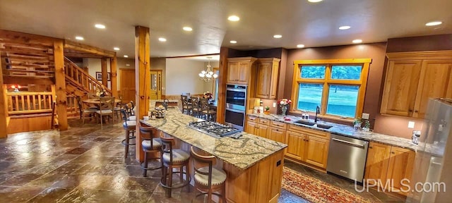 kitchen with light stone counters, a breakfast bar, appliances with stainless steel finishes, a center island, and a notable chandelier