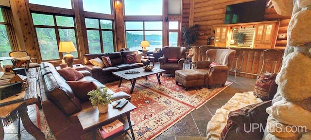 living room featuring log walls, a towering ceiling, and plenty of natural light