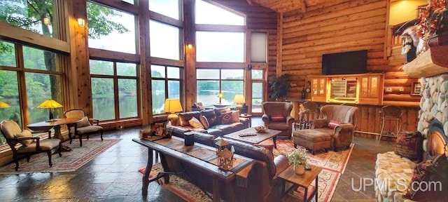 living room with high vaulted ceiling, log walls, and a healthy amount of sunlight