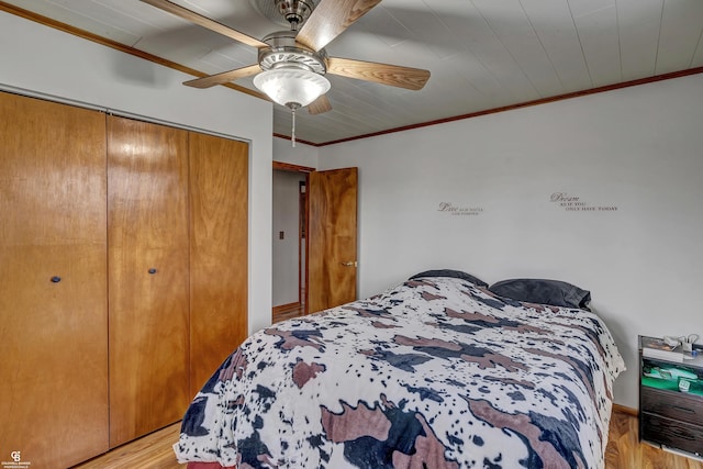 bedroom featuring ornamental molding, light wood-type flooring, a closet, and ceiling fan