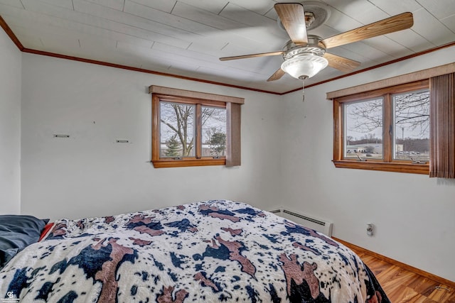 bedroom with hardwood / wood-style floors, ornamental molding, baseboard heating, and ceiling fan