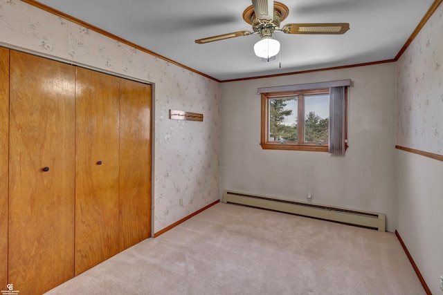 unfurnished bedroom featuring ceiling fan, a baseboard heating unit, a closet, light carpet, and crown molding