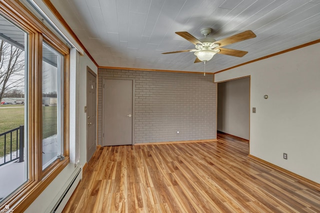 spare room with brick wall, baseboard heating, light wood-type flooring, ceiling fan, and ornamental molding