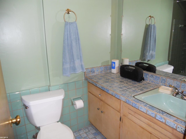 bathroom with vanity, tile walls, and toilet