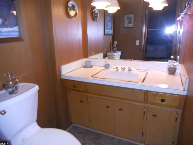 bathroom with vanity, wooden walls, and toilet