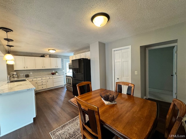 dining room featuring a textured ceiling, dark wood-type flooring, and sink