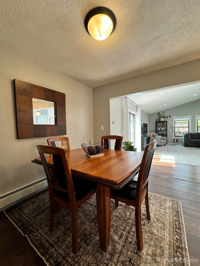 dining space with wood-type flooring, a stone fireplace, a textured ceiling, and lofted ceiling