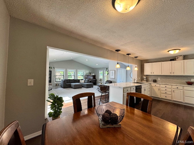 dining space featuring vaulted ceiling, a textured ceiling, hardwood / wood-style flooring, and sink