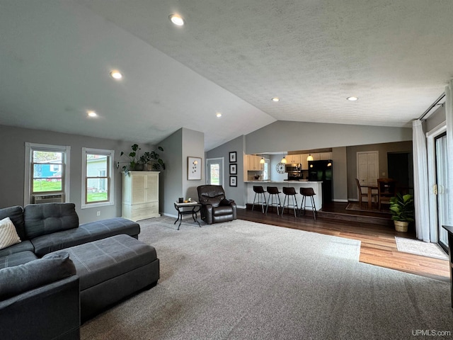 living room featuring wood-type flooring, vaulted ceiling, and a textured ceiling