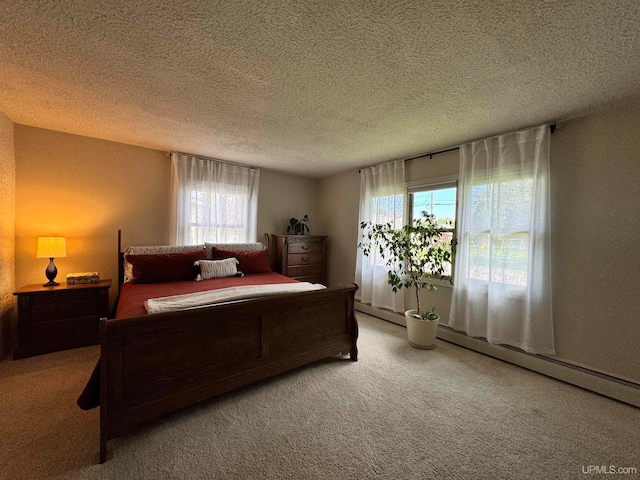 bedroom featuring a baseboard heating unit, carpet, and a textured ceiling