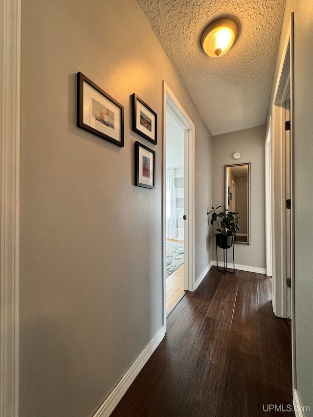 hallway with a textured ceiling and dark hardwood / wood-style floors