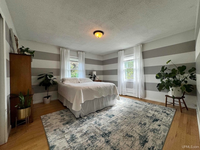 bedroom featuring light hardwood / wood-style floors, multiple windows, and a textured ceiling