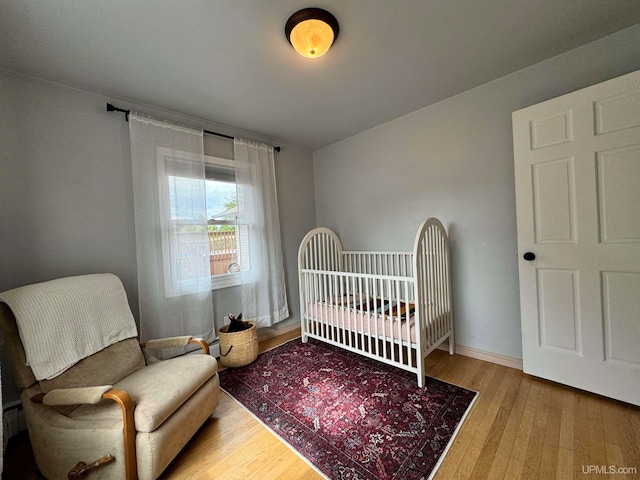 bedroom with wood-type flooring and a nursery area