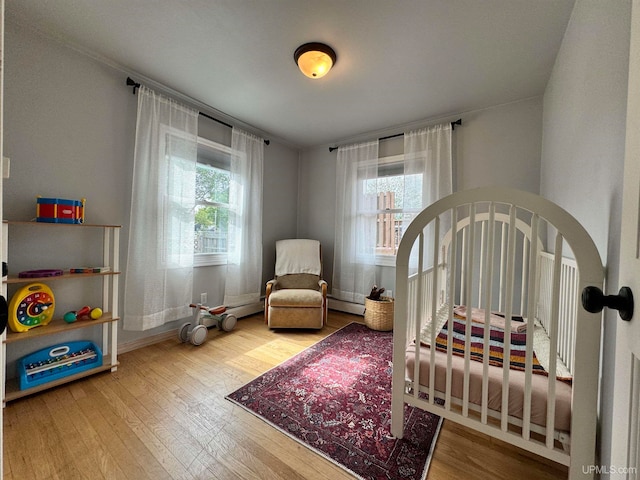 bedroom with a baseboard heating unit and wood-type flooring