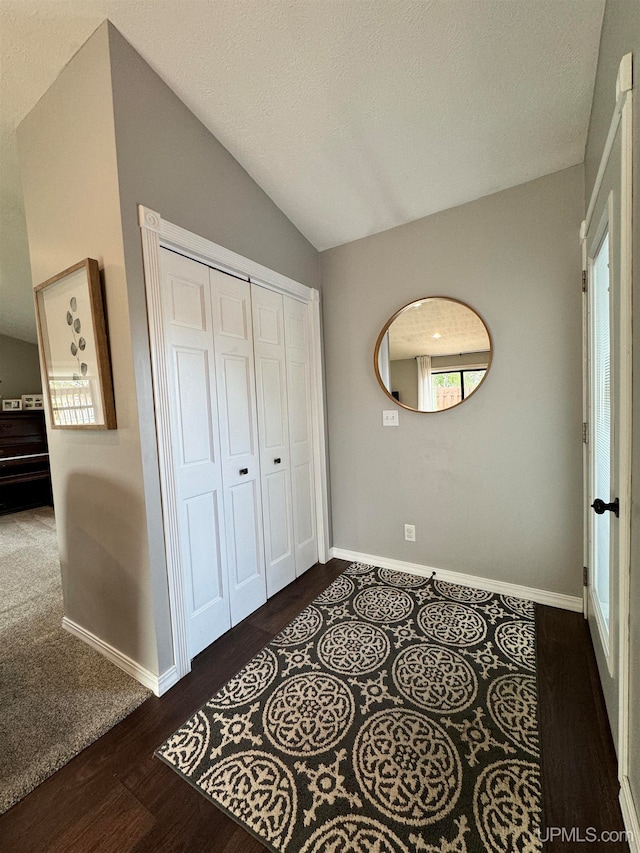 unfurnished bedroom with a textured ceiling, a closet, dark wood-type flooring, and lofted ceiling