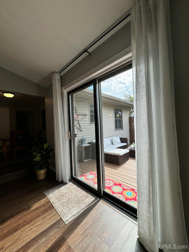 entryway with wood-type flooring, a textured ceiling, and vaulted ceiling