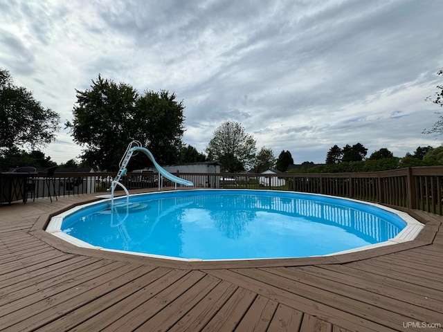 view of swimming pool featuring a water slide and a deck