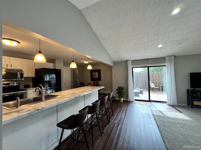 kitchen with white cabinetry, dark wood-type flooring, stainless steel appliances, lofted ceiling, and a kitchen bar