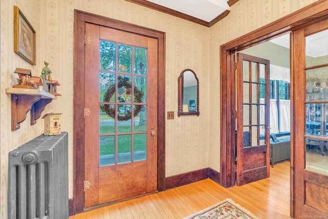 doorway featuring radiator heating unit, hardwood / wood-style floors, and crown molding