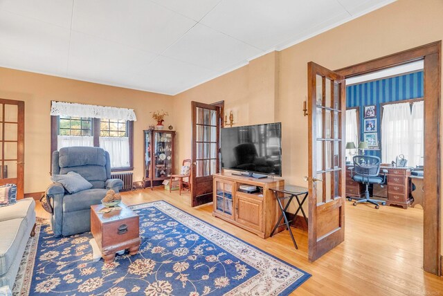 living room featuring wood-type flooring, ornamental molding, and radiator heating unit