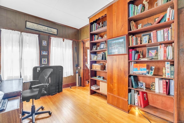 office area featuring light wood-type flooring, wooden walls, and built in features