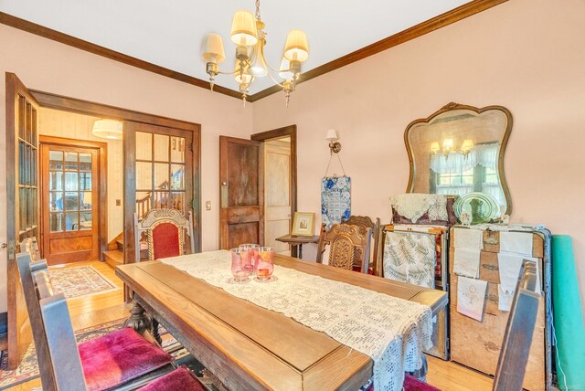 dining room with a notable chandelier, light wood-type flooring, and ornamental molding