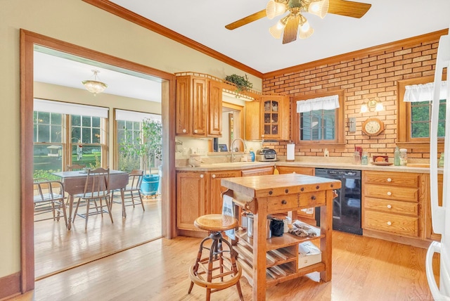 kitchen featuring ceiling fan, dishwasher, light hardwood / wood-style flooring, and brick wall