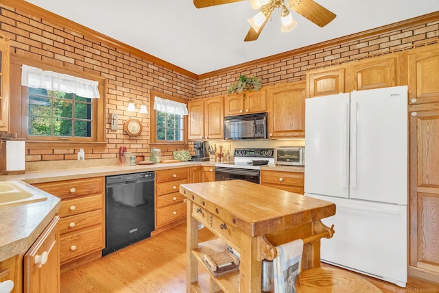 kitchen featuring light hardwood / wood-style floors, brick wall, black appliances, crown molding, and ceiling fan