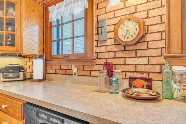 kitchen featuring brick wall and dishwasher