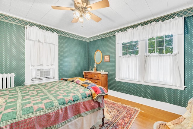 bedroom featuring ornamental molding, wood-type flooring, ceiling fan, and cooling unit