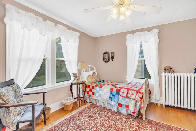 bedroom featuring radiator heating unit, ceiling fan, and hardwood / wood-style floors