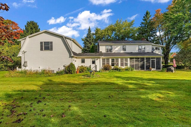 rear view of property featuring a sunroom and a yard