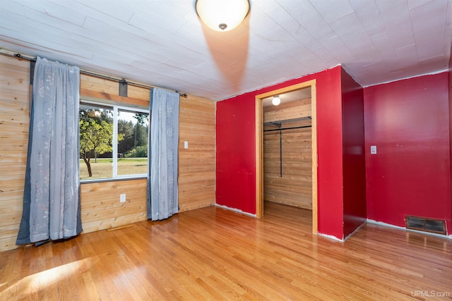 unfurnished room featuring hardwood / wood-style flooring, wooden walls, and a barn door