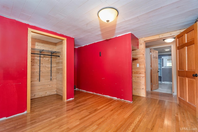 unfurnished bedroom featuring light wood-type flooring and wood walls