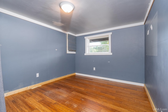 spare room featuring wood-type flooring and ornamental molding