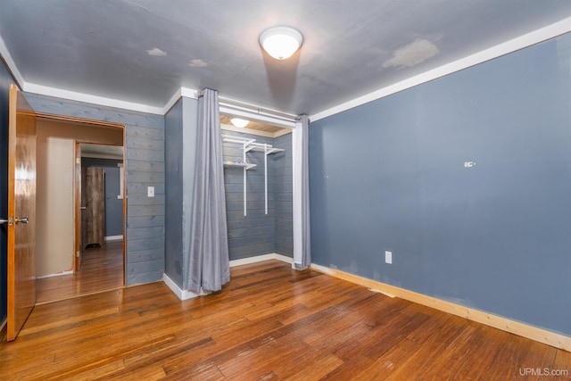 unfurnished bedroom featuring wooden walls and hardwood / wood-style floors