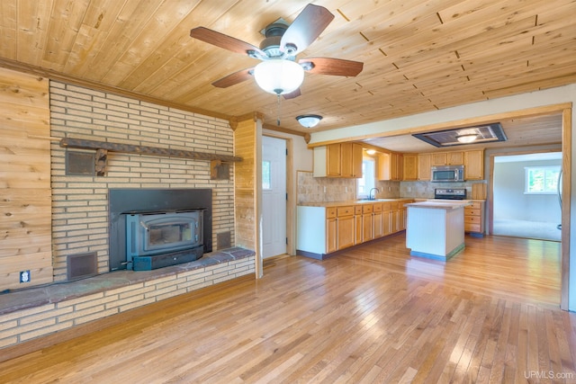 kitchen with ceiling fan, wood ceiling, wood walls, a kitchen island, and light hardwood / wood-style flooring