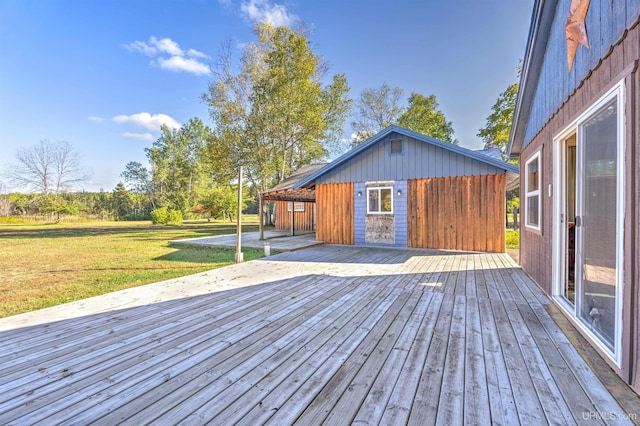 wooden terrace featuring a lawn and an outbuilding