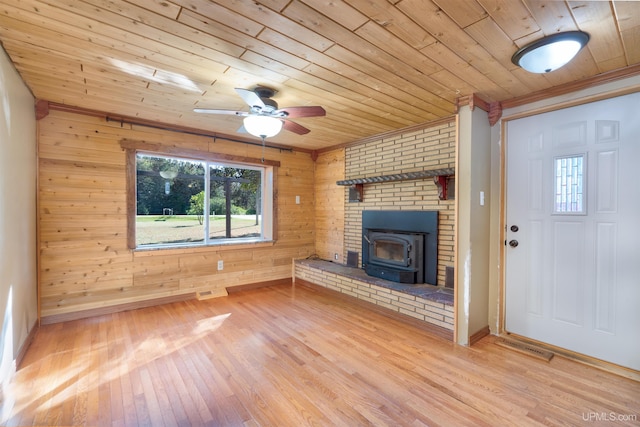 unfurnished living room featuring light wood-type flooring, wooden walls, ceiling fan, and wooden ceiling