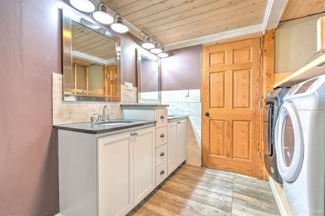 laundry room with cabinets, light hardwood / wood-style floors, sink, separate washer and dryer, and wooden ceiling