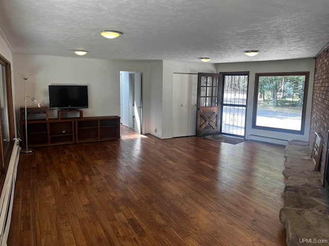 unfurnished living room with a baseboard heating unit, a large fireplace, a textured ceiling, and dark wood-type flooring