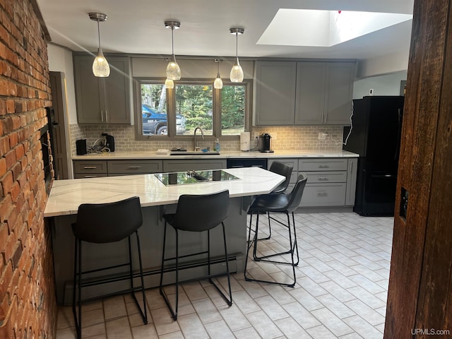 kitchen with black appliances, sink, a skylight, and tasteful backsplash