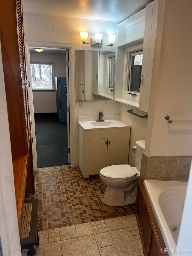 bathroom with a tub to relax in, vanity, and toilet