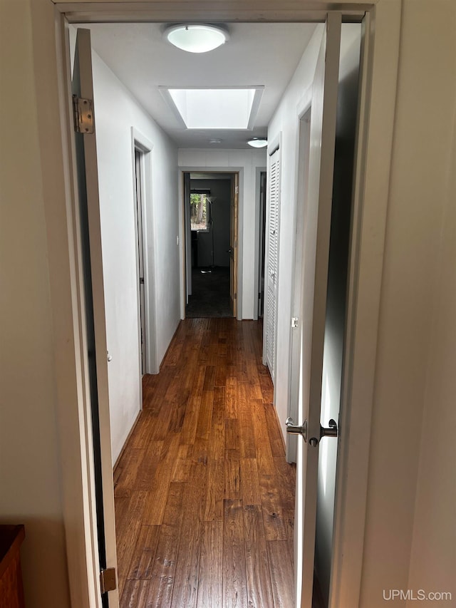 hall with a skylight and dark wood-type flooring