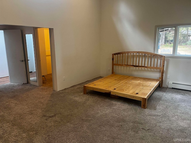 unfurnished bedroom featuring a baseboard heating unit and dark colored carpet