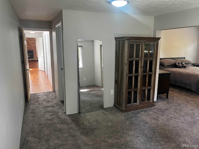 hallway with dark colored carpet and a textured ceiling