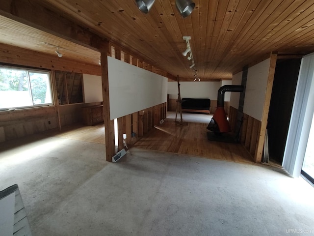 basement with wooden walls, light hardwood / wood-style flooring, wood ceiling, and a wood stove