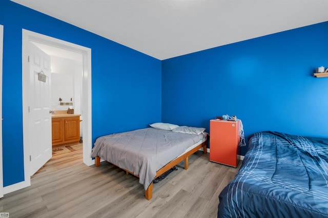 bedroom with light hardwood / wood-style flooring and ensuite bath