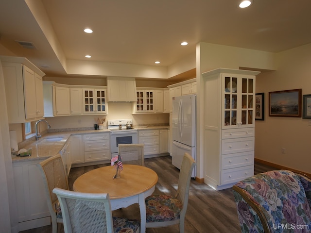 kitchen with white appliances, sink, dark wood-type flooring, and white cabinets